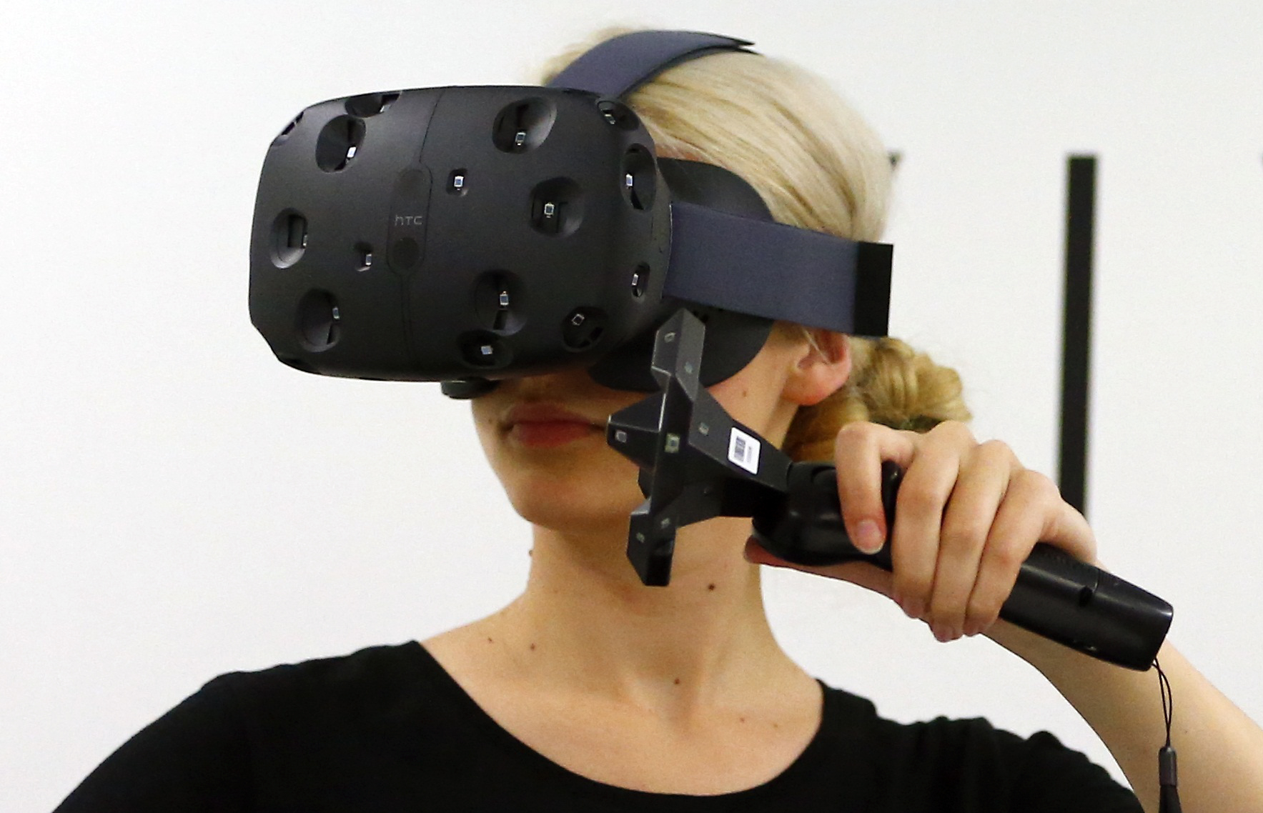 A woman checks a pair of Vive Virtual Reality goggles, produced by Taiwan's HTC, during the Gamescom 2015 fair in Cologne